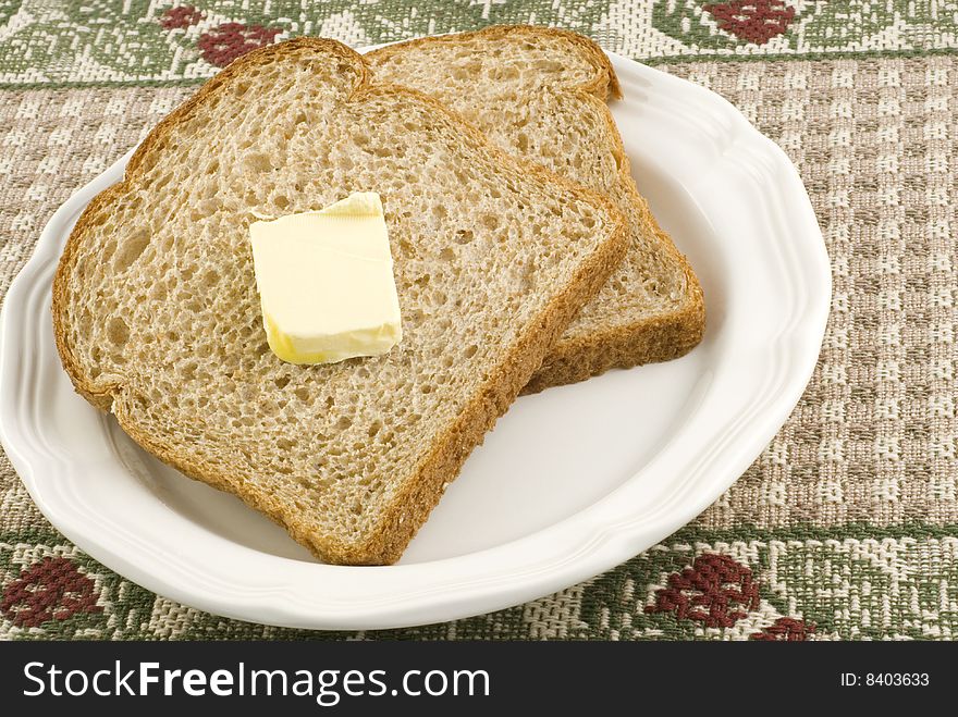 Two slices of whole wheat bread and butter on a plate with copy space. Two slices of whole wheat bread and butter on a plate with copy space