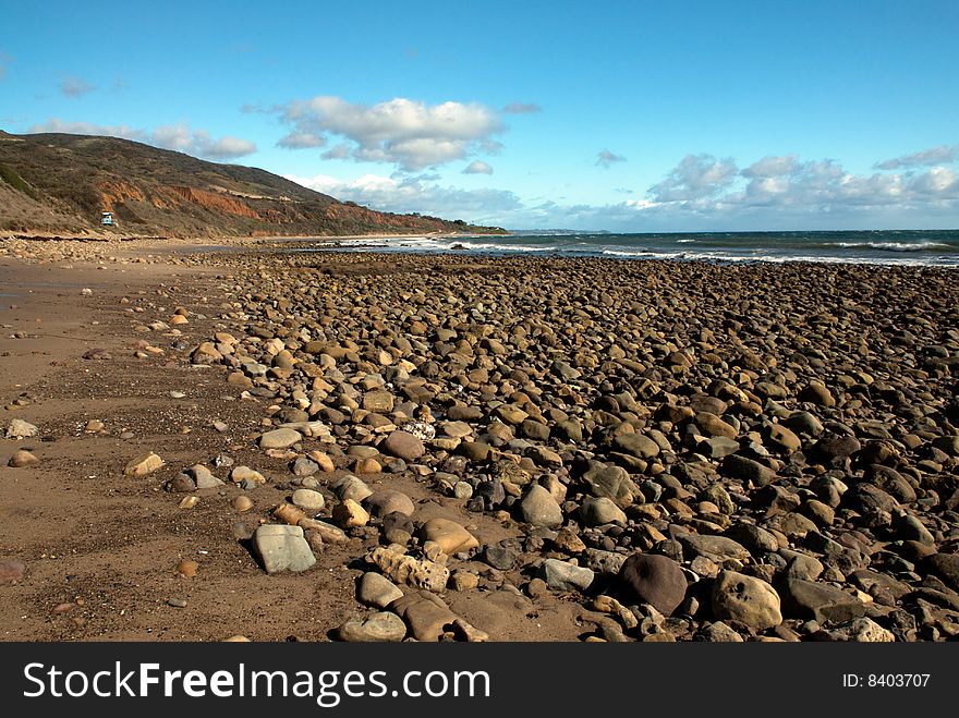 A rock covered beach in beautiful southern California with a blue sky and clouds. A rock covered beach in beautiful southern California with a blue sky and clouds