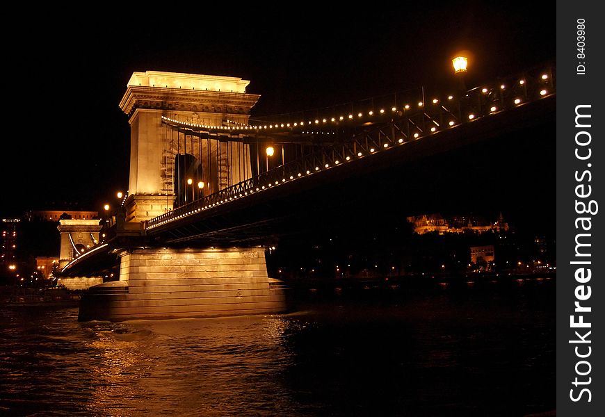 The historic Chain Bridge over the Danube, in Budapest, Hungary, all lit up at night.