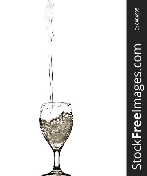 A stream of water splashing into and filling a wine glass. A stream of water splashing into and filling a wine glass.