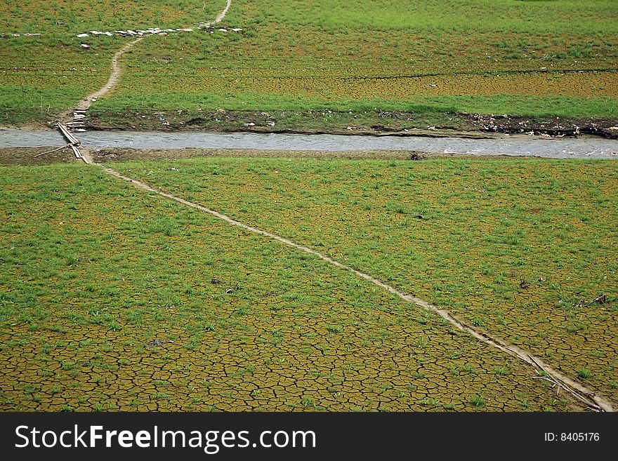 A narrow road going through a grass field and stream. A narrow road going through a grass field and stream.