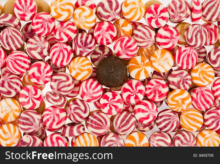 Background from round multi-coloured sweets with one chocolate sweet