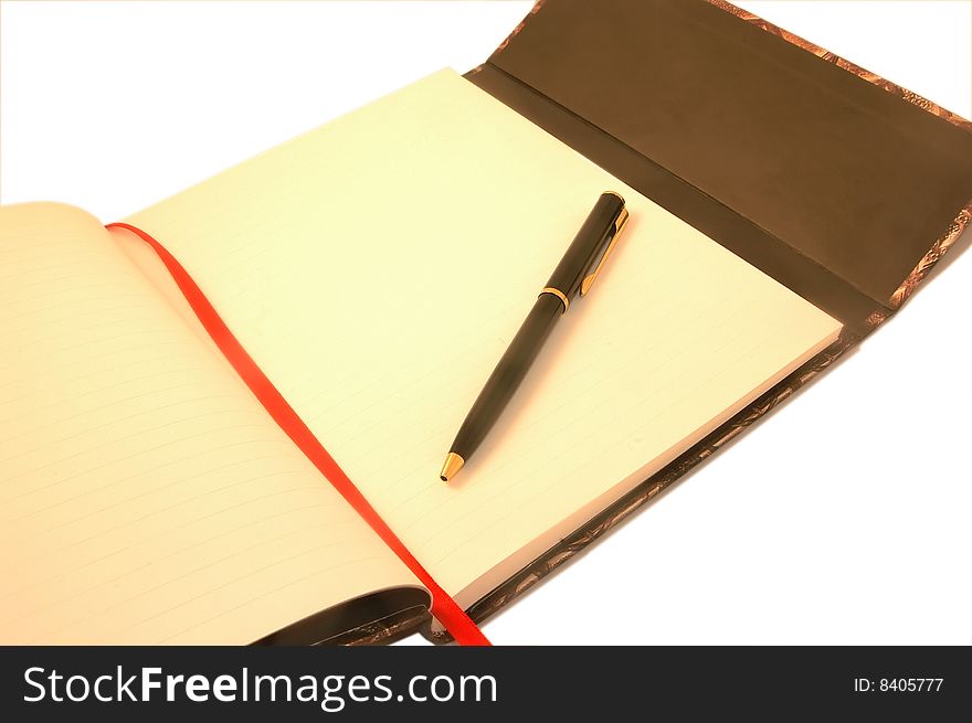 A pen lying on an open notebook, blank page showing. A pen lying on an open notebook, blank page showing