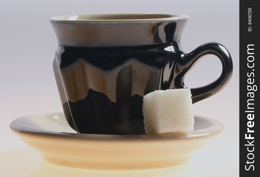 Black cup of tea and sugar isolated on a white background