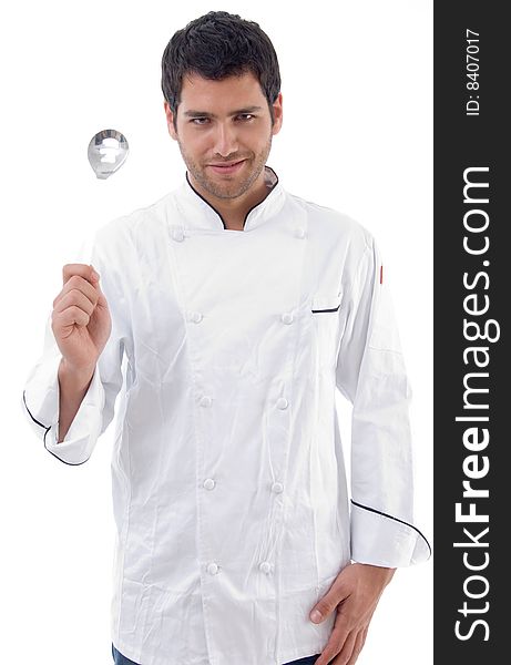 Young chef holding slotted spoon against white background