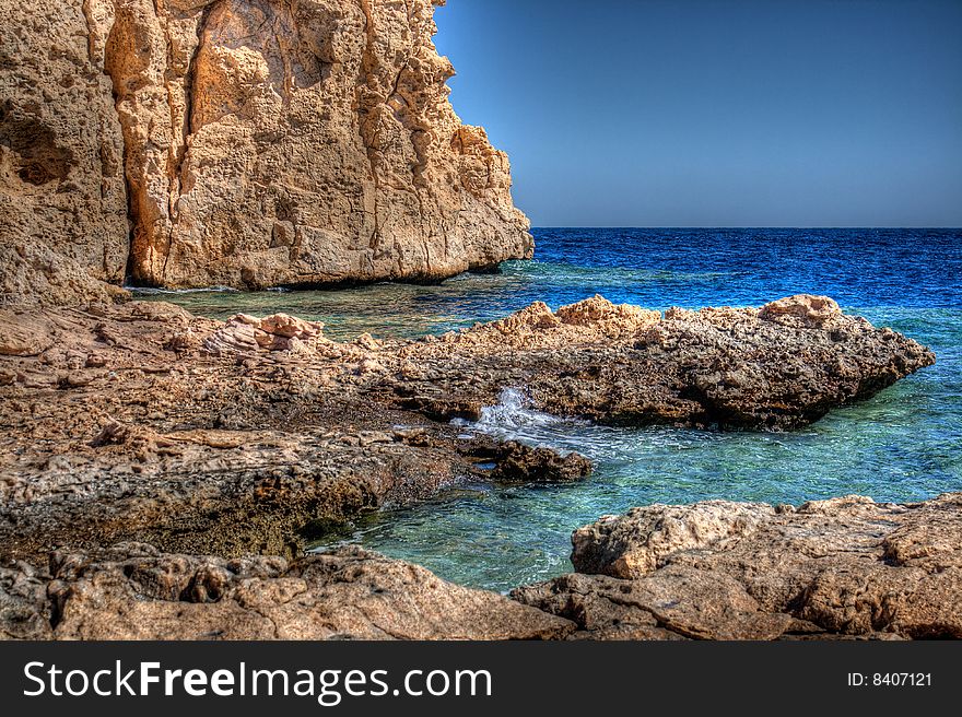 Rock steep coast on blue sea. Rock steep coast on blue sea