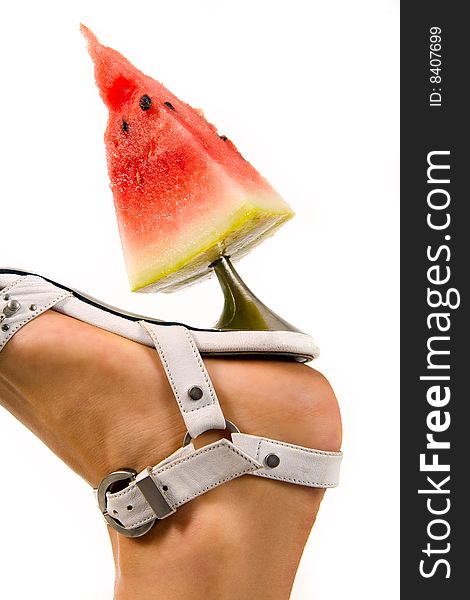 Woman's leg in high heel with slice of watermelon on heel. Woman's leg in high heel with slice of watermelon on heel