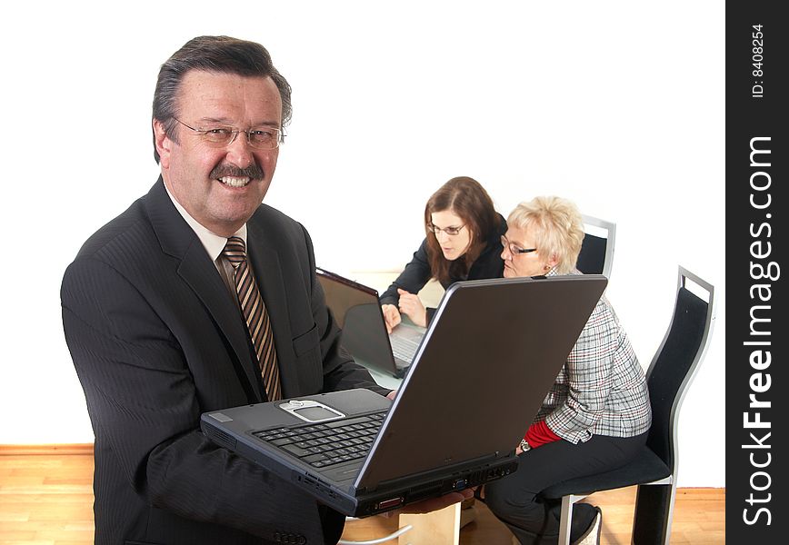 Businessman in office environment with laptop. Three people with focus on mature boss in front. Isolated over white. Businessman in office environment with laptop. Three people with focus on mature boss in front. Isolated over white.