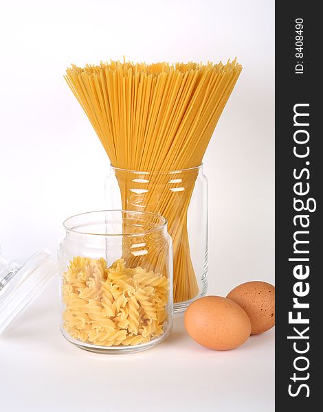 Pasta in bowl and eggs on white background