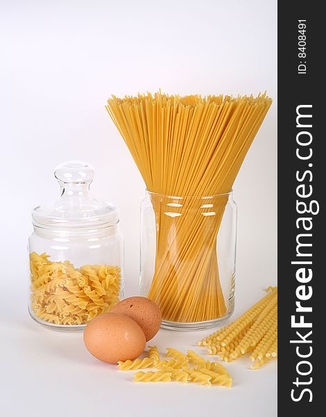 Pasta in bowl and eggs on white background