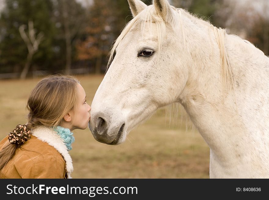 A young girl kisses her horse on a cold gray day in Vermont. A young girl kisses her horse on a cold gray day in Vermont