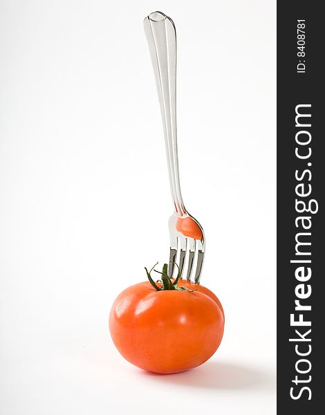 Tomato and fork on white background