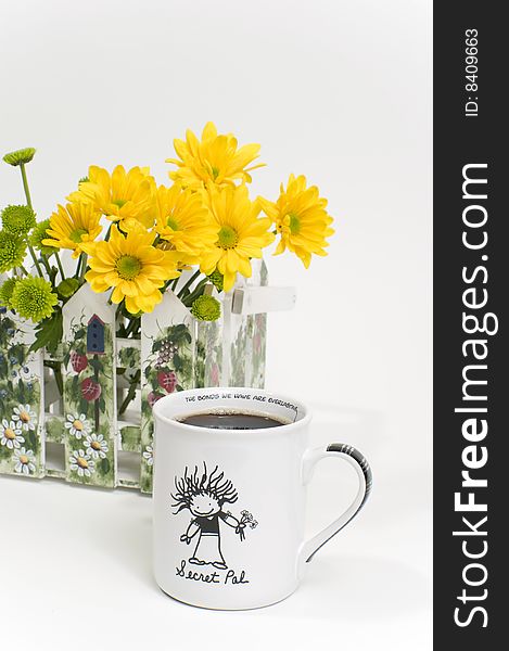 A cup of hot coffee with decorative yellow daisies in the background. A cup of hot coffee with decorative yellow daisies in the background.