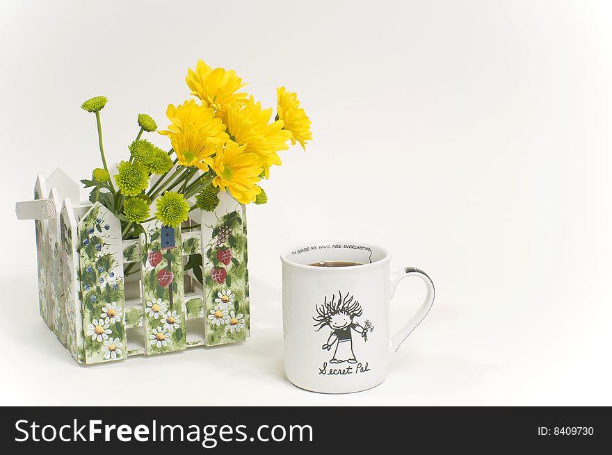 A coffee mug with yellow daisies in a holder on white background. A coffee mug with yellow daisies in a holder on white background.