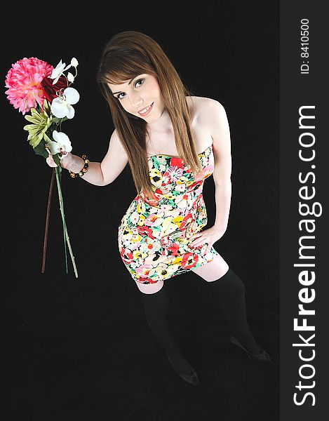 Female model holding a bunch of flowers against a black back drop wearing a flowery dress. Female model holding a bunch of flowers against a black back drop wearing a flowery dress