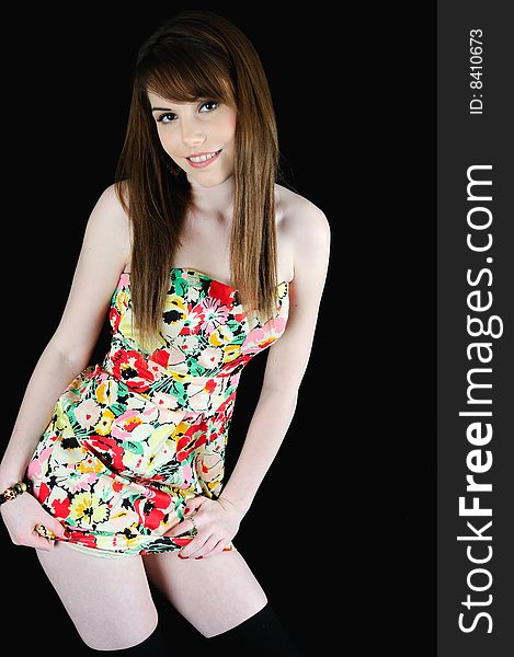 Female model standing against a black back drop smiling at the camera in a summery dress. Female model standing against a black back drop smiling at the camera in a summery dress