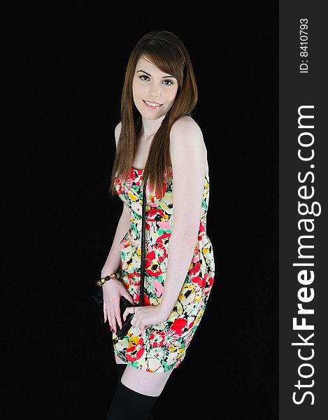 Female model standing against a black back drop smiling at the camera wearing a flower pattern dress. Female model standing against a black back drop smiling at the camera wearing a flower pattern dress