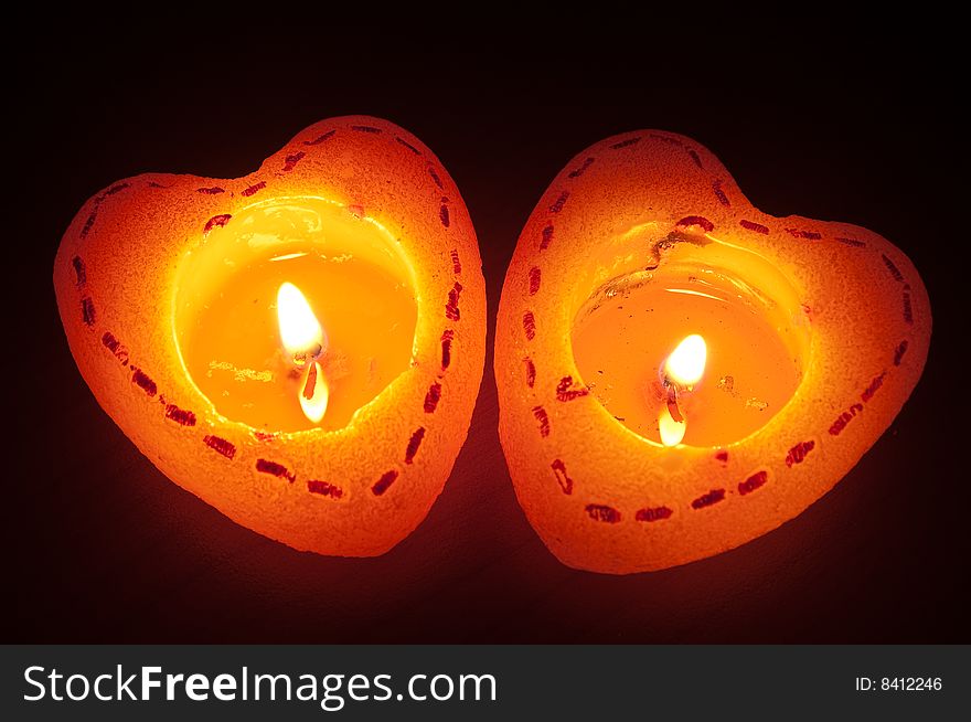 Two burning heart candles in dark