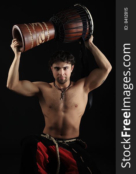 Handsome drummer playing the african drum. Shot in a studio. Handsome drummer playing the african drum. Shot in a studio.