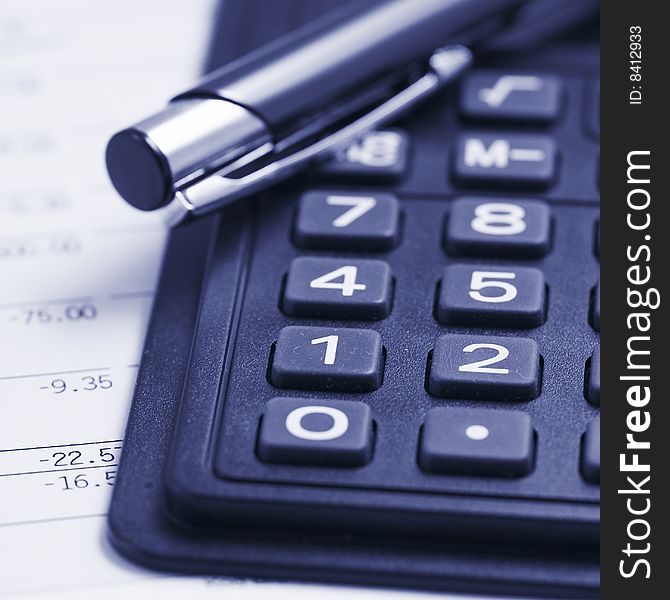 Close up of a calcilator with pen and financial data. Close up of a calcilator with pen and financial data