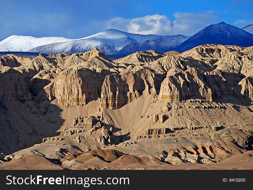 Clay mountains backgrounded with the snow-capped Himalayas