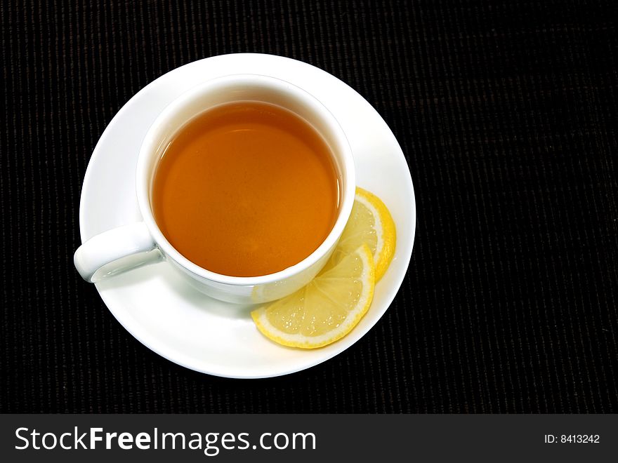 Cup of Tea with Lemon pieces over black background