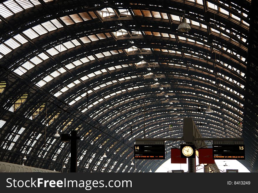 Image of the roof  of  a train Station with a clock and the info signs