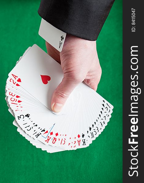 A fan of mixed playing cards on a green felt background with an ace up the sleeve. A fan of mixed playing cards on a green felt background with an ace up the sleeve