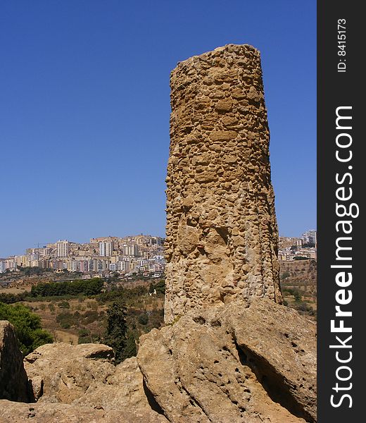 Column of an ancient greek temple and the city of Agrigento in the background. Column of an ancient greek temple and the city of Agrigento in the background