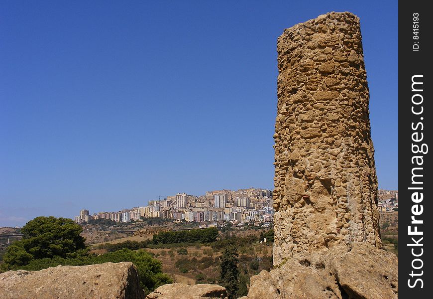 Column of an ancient greek temple and the city of Agrigento in the background. Column of an ancient greek temple and the city of Agrigento in the background