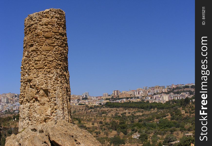 Column of an ancient greek temple and the city of Agrigento in the background. Column of an ancient greek temple and the city of Agrigento in the background