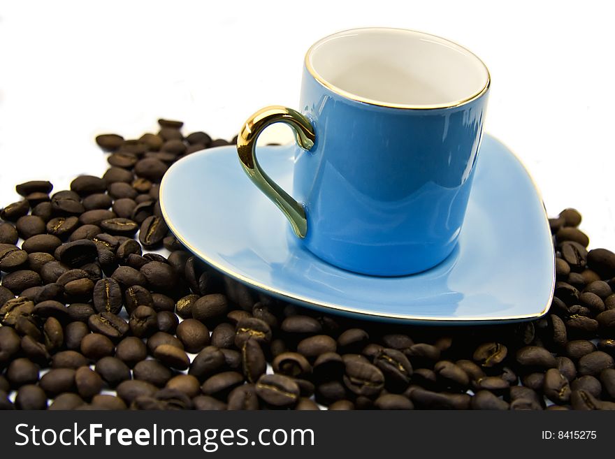 Blue cup and saucer with grains of coffee close up