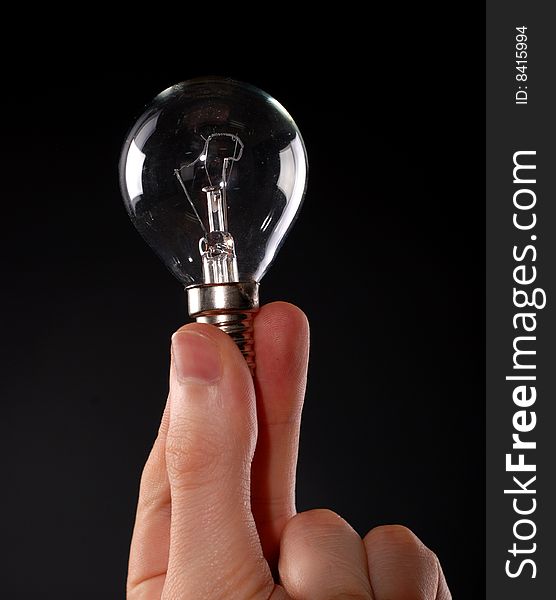 Electric lamp in male fingers at black background