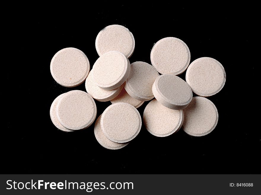Group of white round pills at black background