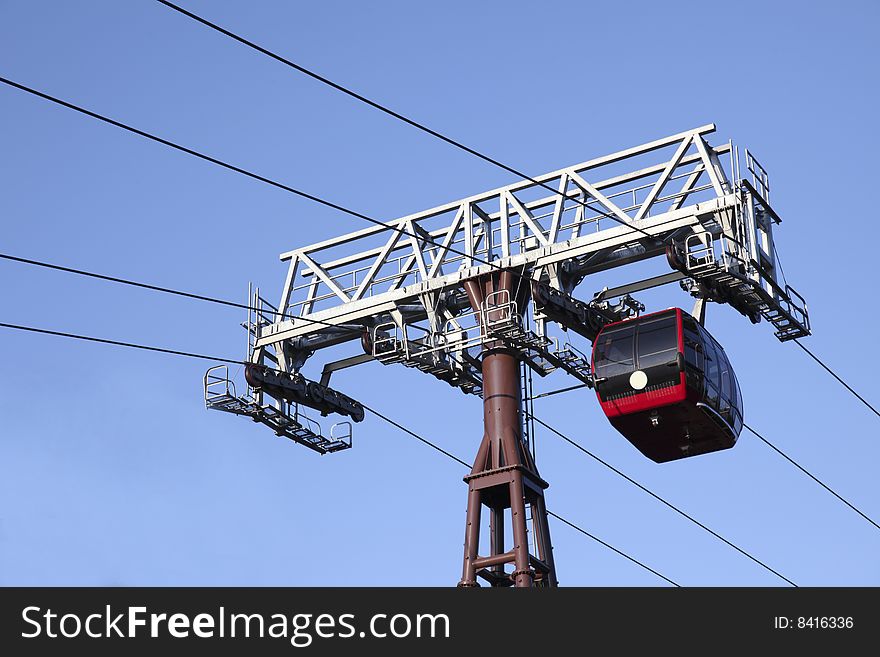 Red cable car isolated on blue sky background.