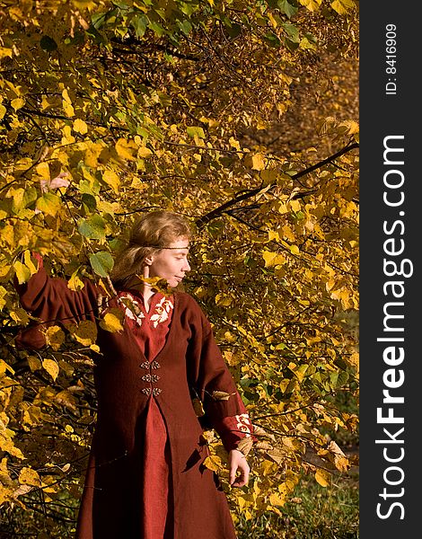 The blonde girl in medieval red dress in the autumn forest. The blonde girl in medieval red dress in the autumn forest