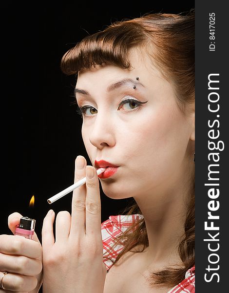 Pin-up style retro woman  lighting-up a cigarette over dark background. Pin-up style retro woman  lighting-up a cigarette over dark background