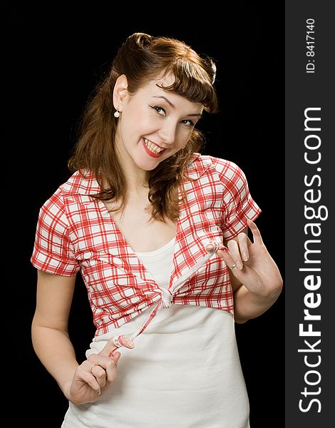 Pretty retro-style woman playing with her chequered blouse, smiling and looking at the camera over dark background. Pretty retro-style woman playing with her chequered blouse, smiling and looking at the camera over dark background