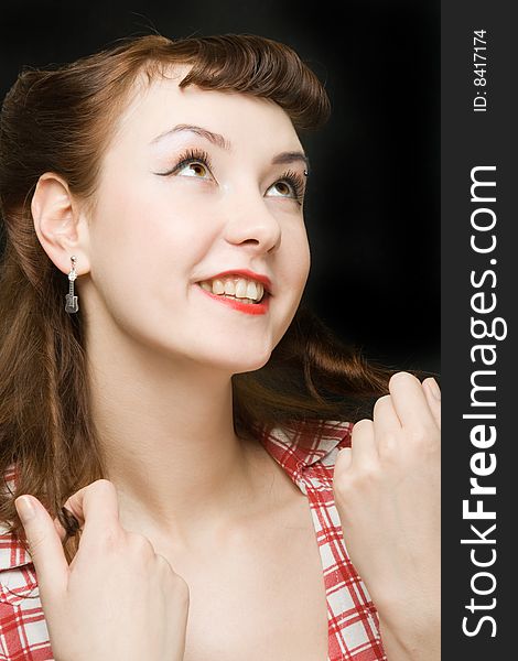 Pretty retro-style woman touching her hair, smiling and looking up over dark background. Pretty retro-style woman touching her hair, smiling and looking up over dark background