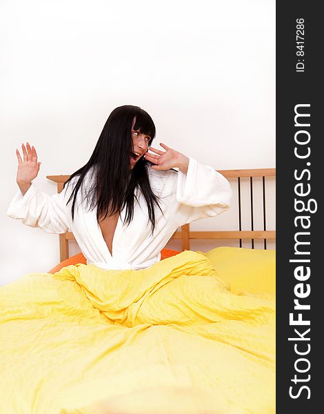 Woman in bed stretching in bathrobe. Woman in bed stretching in bathrobe