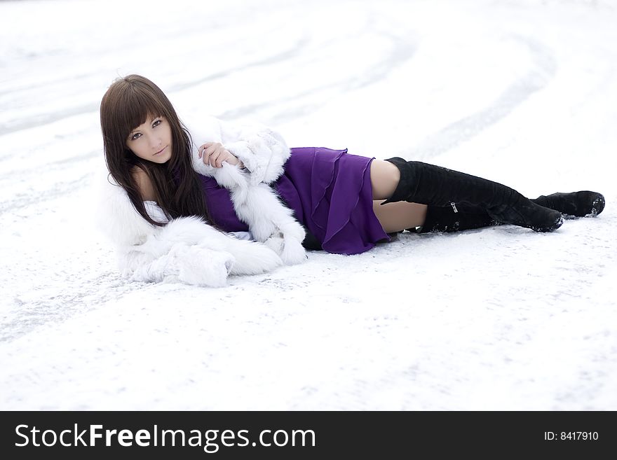 Picture of a girl who lies on the snow in the purple dress. Picture of a girl who lies on the snow in the purple dress