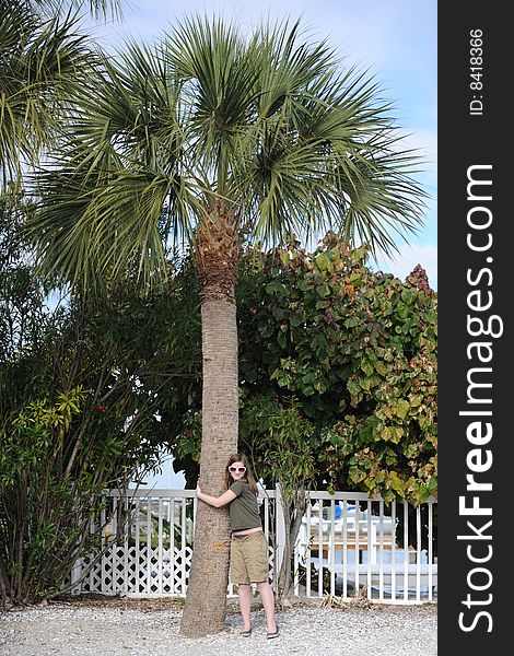 A northern preteen girl hugging a palm tree she's delighted to see for the first time. A northern preteen girl hugging a palm tree she's delighted to see for the first time.