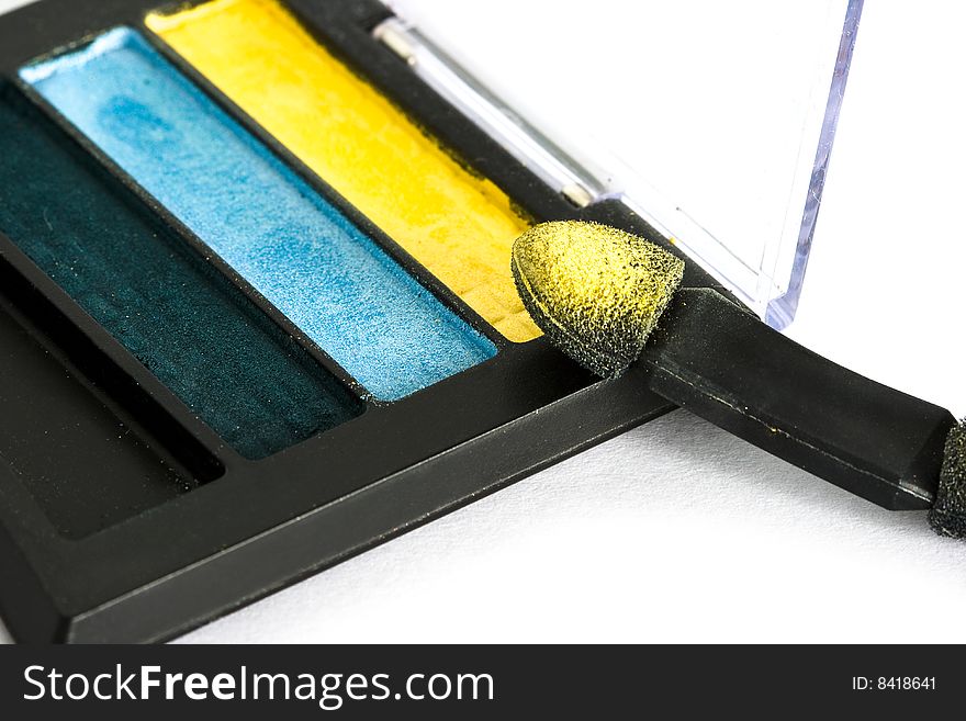 Yellow and blue make-up eyeshadows and cosmetic brush