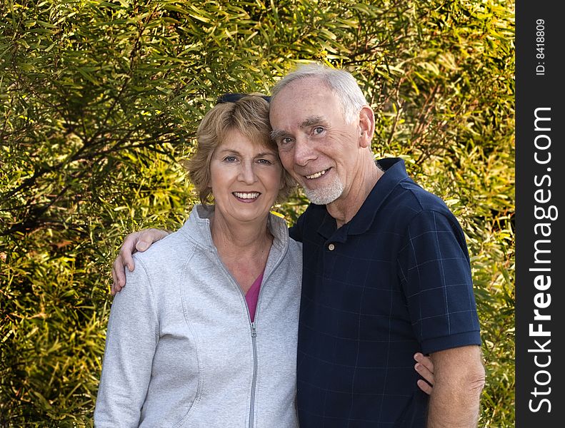 Happily married senior couple in front of lush foliage. Happily married senior couple in front of lush foliage