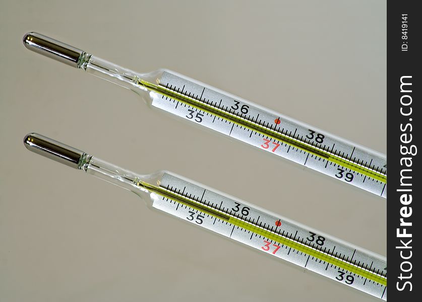 Two clinical thermometers marked in Celsius degrees, one shows body temperature lower than normal and another shows higher than normal.