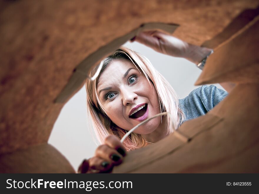 Young woman with positively surprised face looking at something in the paper shopping bag. Young woman with positively surprised face looking at something in the paper shopping bag.