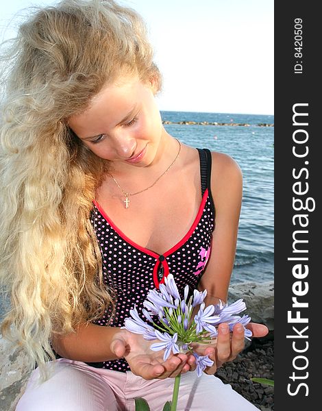 Blond girl looking at blue flower. Blond girl looking at blue flower.