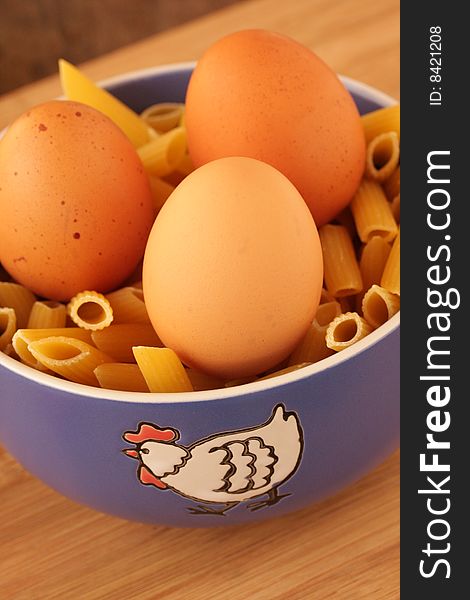 Blue bowl with chook picture, filled with raw pasta and 3 eggs. Blue bowl with chook picture, filled with raw pasta and 3 eggs