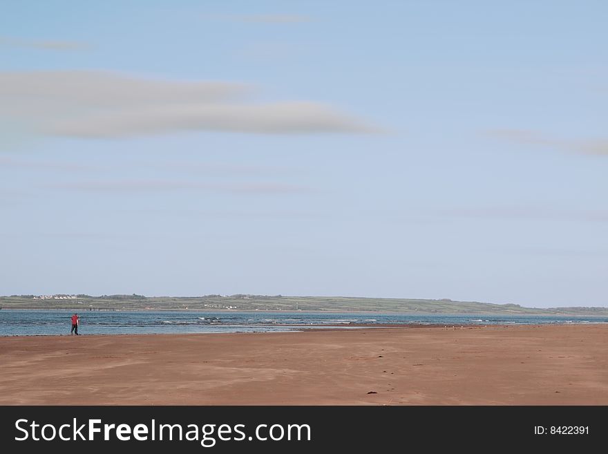 Man walking on beale beach co kerry ireland on a cold winters morning with turbines in the background. Man walking on beale beach co kerry ireland on a cold winters morning with turbines in the background