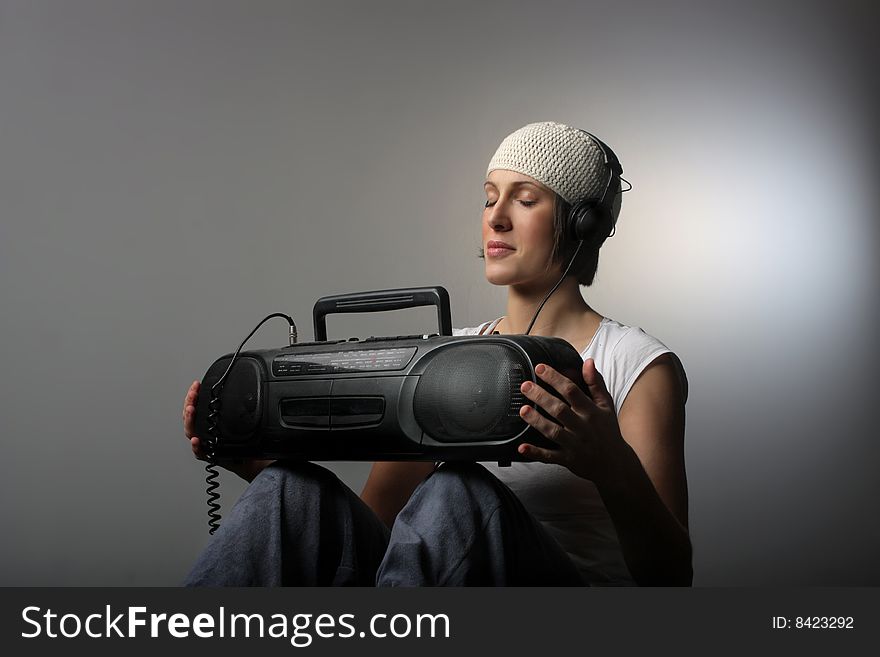 A cool looking girl listening music with stereo and headphones